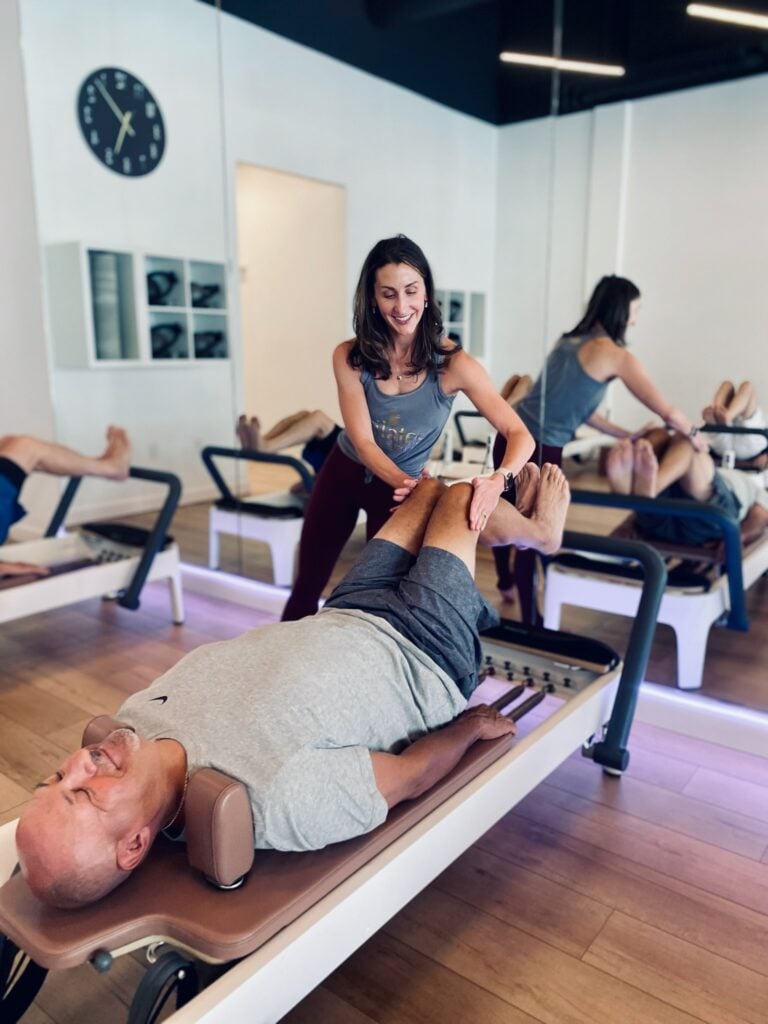 Katie Sovenyhazy coaching a client on the reformer at Pilates of Charleston